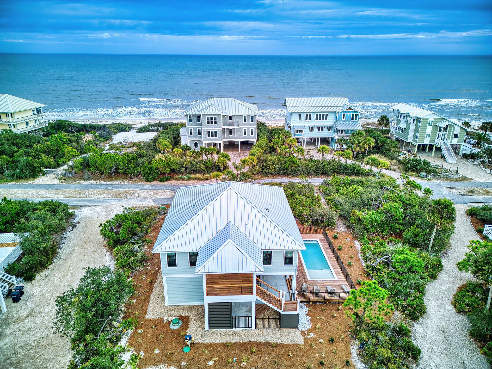 A coastal property with multiple houses, a swimming pool, and a view of the ocean.