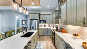 A modern kitchen with a central island, stainless steel appliances, and light wood cabinetry. - Brand New Construction, 4 BR Private Pool Plantation Home (ST GEORGE ISLAND)