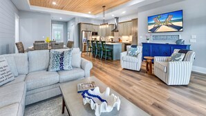 A modern living room with a grey sofa, striped armchairs, and a coffee table. - Brand New Construction, 4 BR Private Pool Plantation Home (ST GEORGE ISLAND)