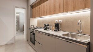 Et moderne køkken med en træbeklædt væg, stålvask og indbyggede hårde hvidevarer.