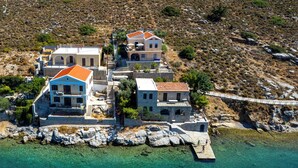 A coastal property with multiple buildings, a dock, and clear turquoise waters. - Villa in Symi, with sea view (simi)