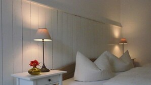 A bedroom with a white bed, white nightstand, and two lamps.