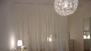 Un dormitorio con cama, mesita de noche con lámpara, cómoda y espejo.