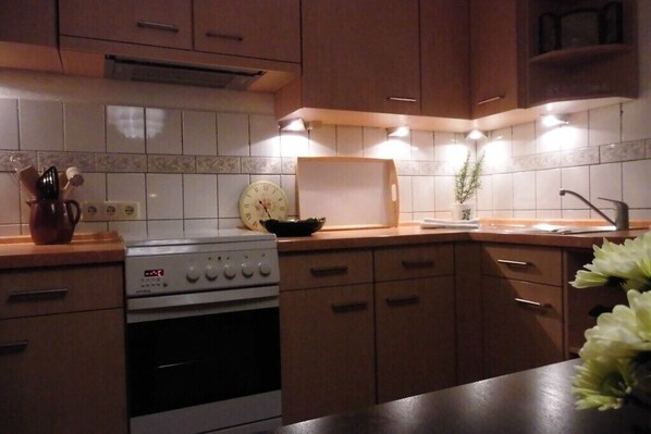 A kitchen with wooden cabinets, a stove, a microwave, and a sink.