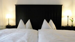 Une chambre d’hôtel avec un grand lit, deux tables de chevet et une tête de lit sombre.