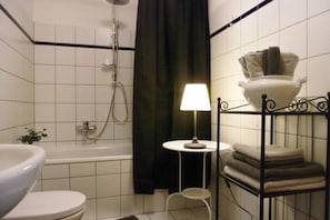 Ein Badezimmer mit Badewanne, Toilette und einem kleinen Tisch mit Lampe.