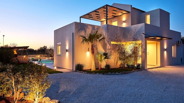 A modern house with a pool, outdoor lighting, and a well-maintained garden.