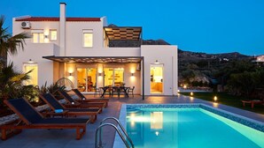 A modern two-story house with a swimming pool, outdoor seating, and a mountain backdrop.