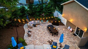 A patio area with a curved seating arrangement, a dining table, and lounge chairs. - Pickleball Paradise - Heated Pool-Hot Tub-Game Room (Tampa)