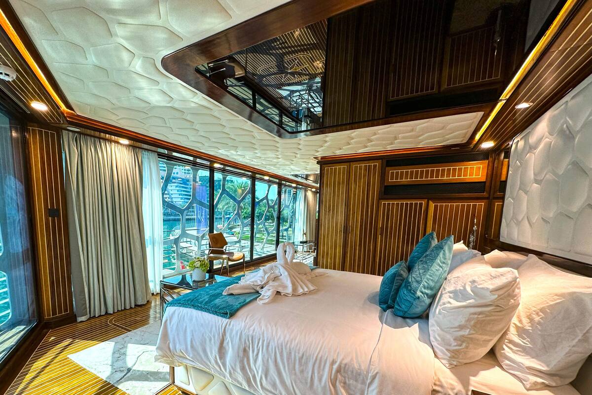 A modern hotel room with a large bed, a view of the city, and a unique ceiling design.