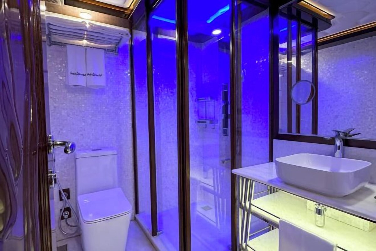 Un baño moderno con ducha de vidrio, lavamanos blanco y retrete a la vista.