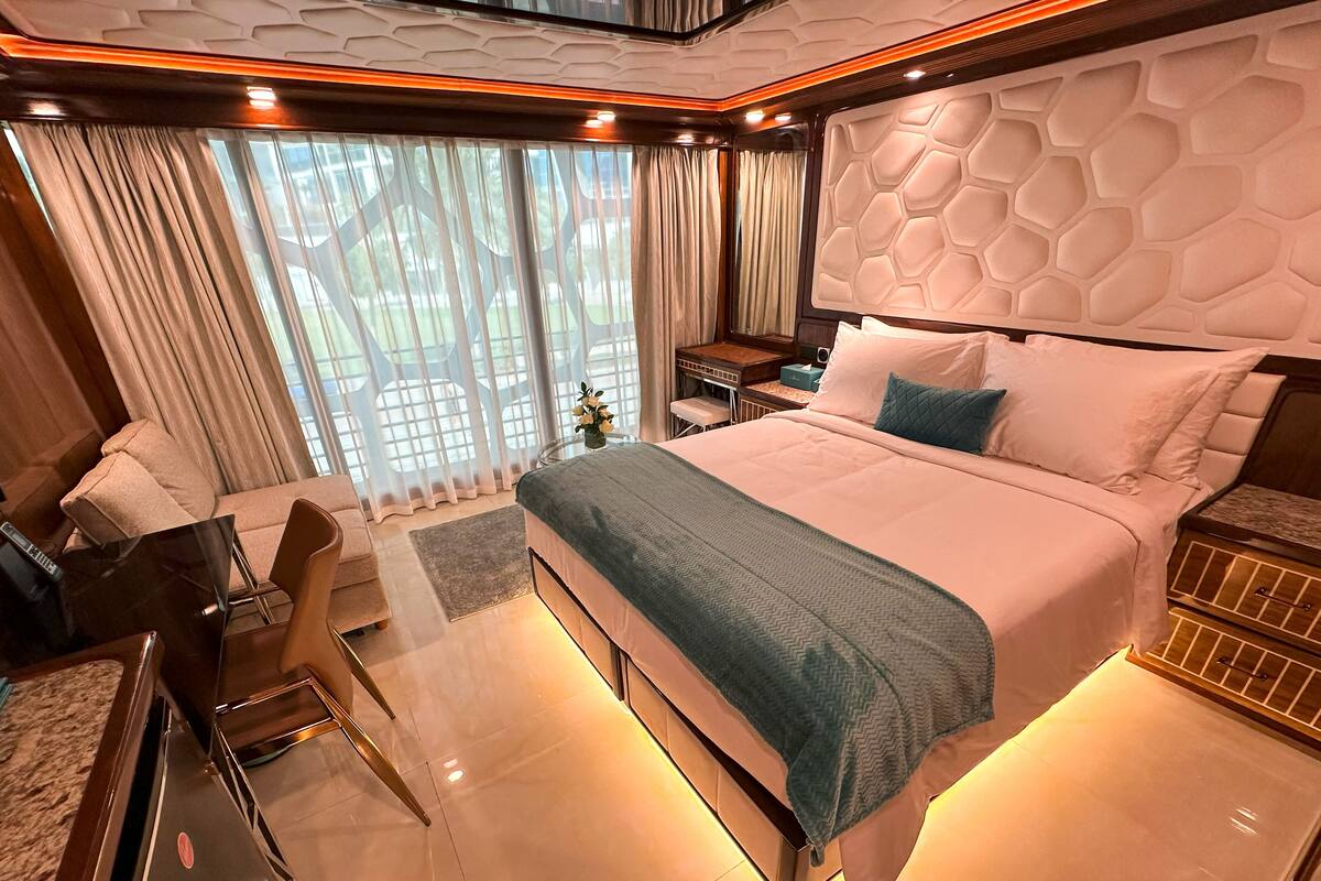 A modern bedroom with a large bed, a desk, and a chair.