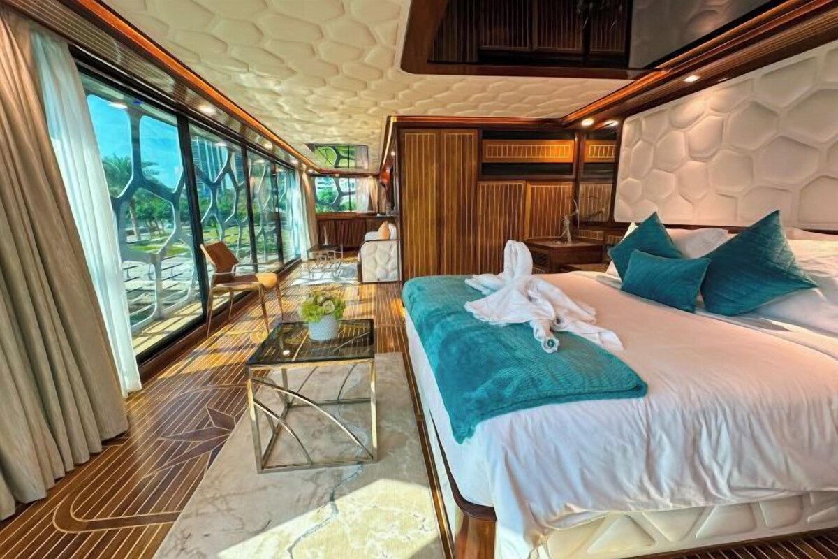 Une chambre luxueuse dotée d’un grand lit, d’un balcon vitré et d’un aménagement intérieur moderne.
