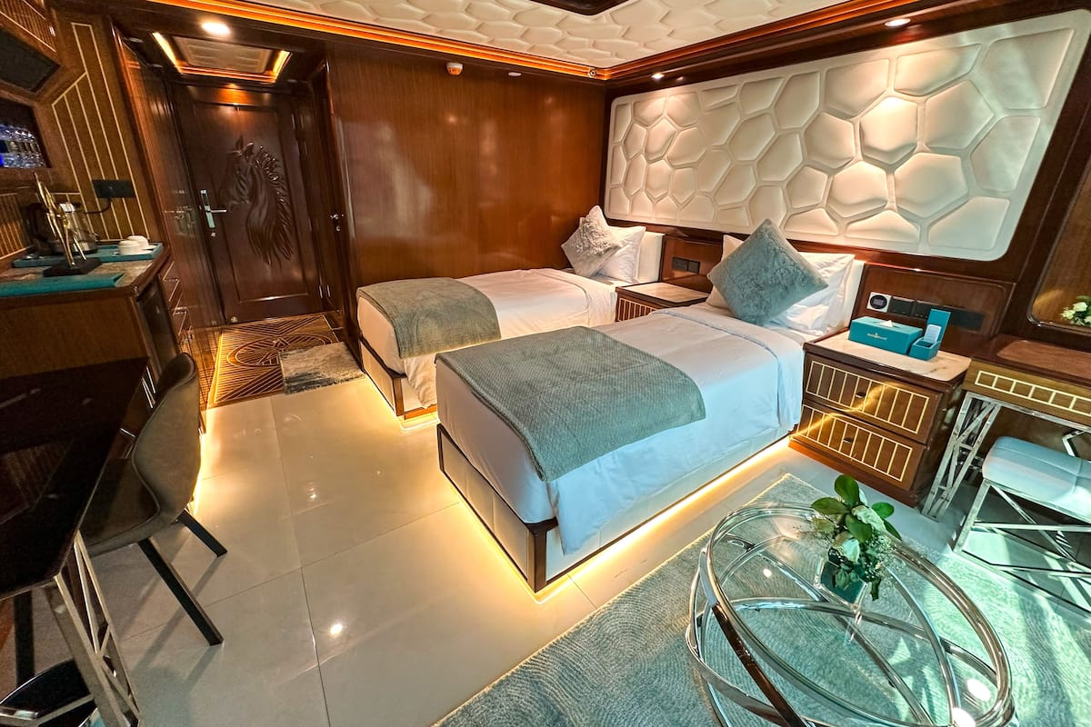 A modern hotel room with two beds, a desk, and a glass coffee table.