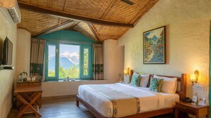 A bedroom with a wooden bed, a window with curtains, a painting on the wall, and a ceiling fan. - Tree of Life Birdsong Chalets (Dharamshala)