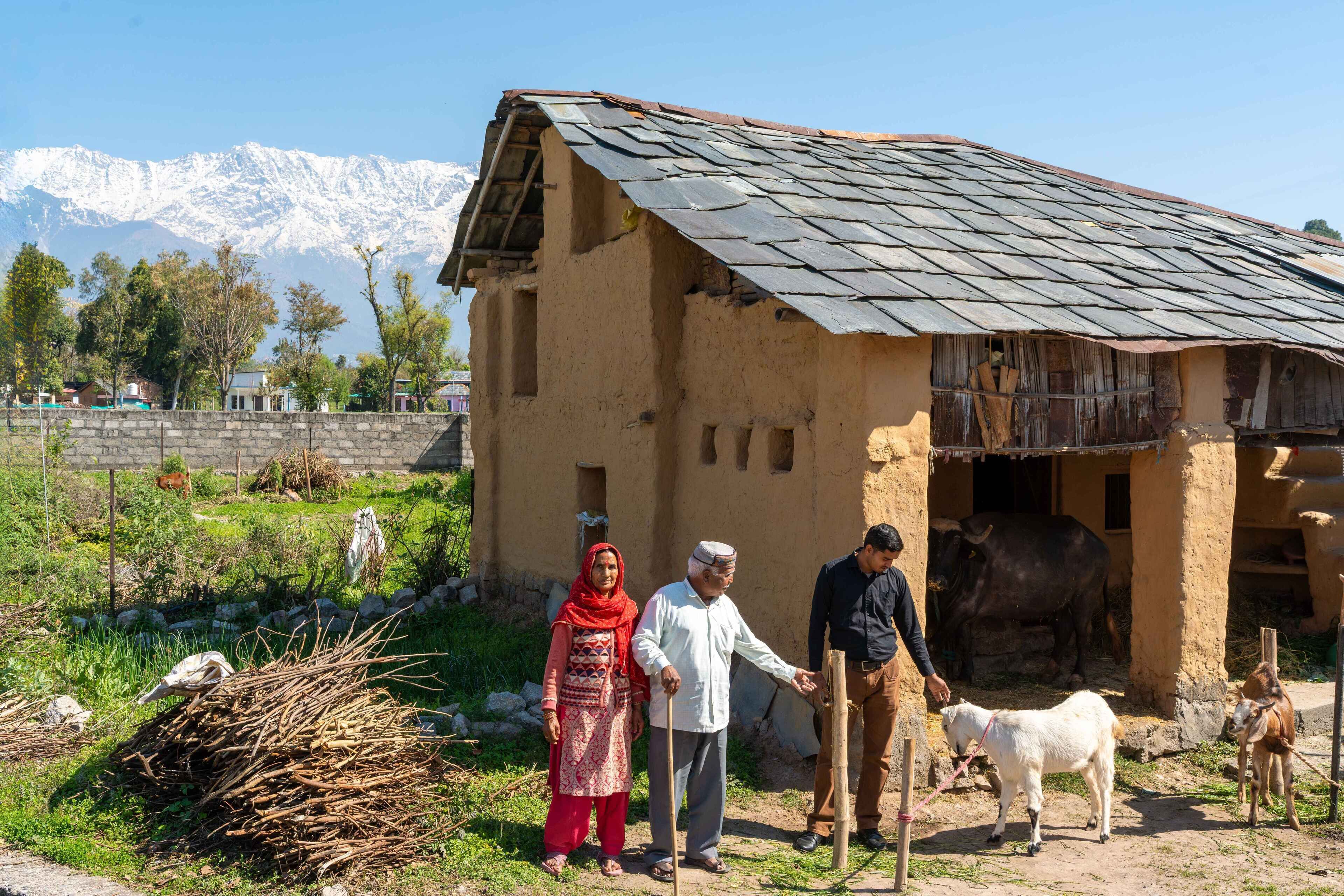 A rustic building with a sloped roof, a stone wall in the background, and a mountainous landscape.