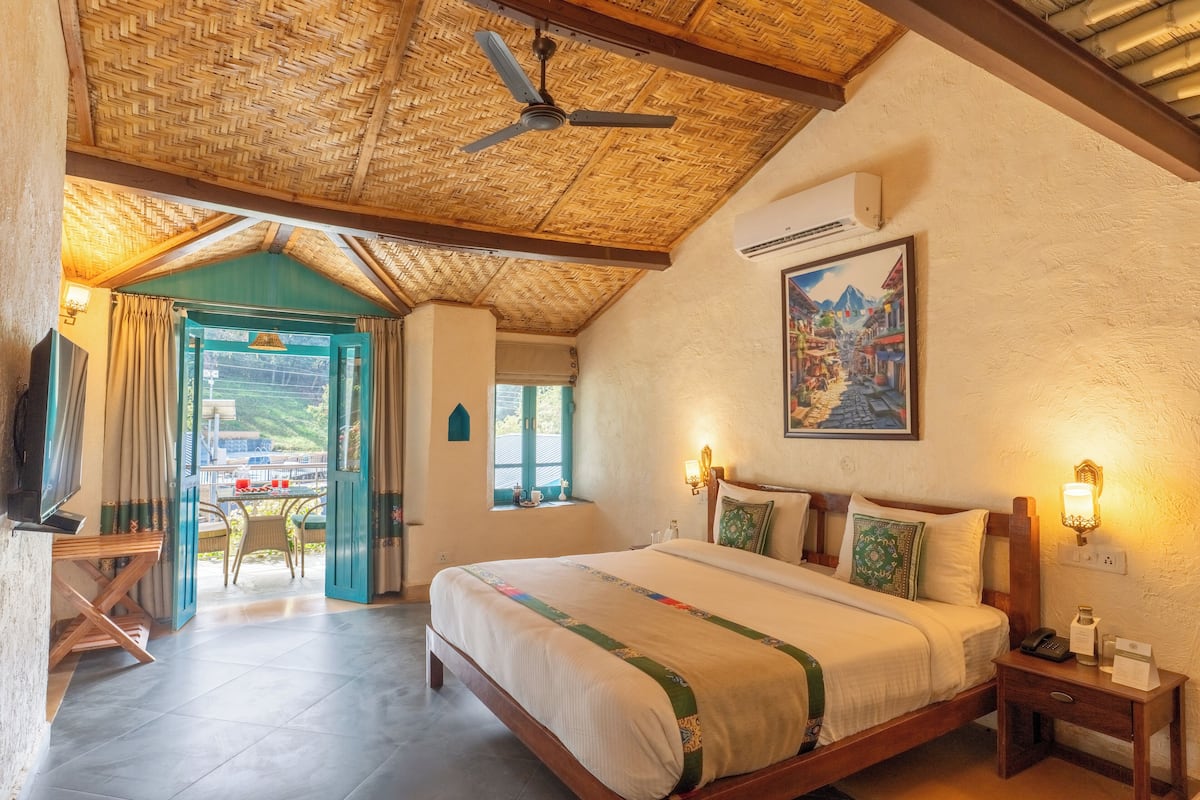 A bedroom with a bed, bedside table, and a view of the outside.