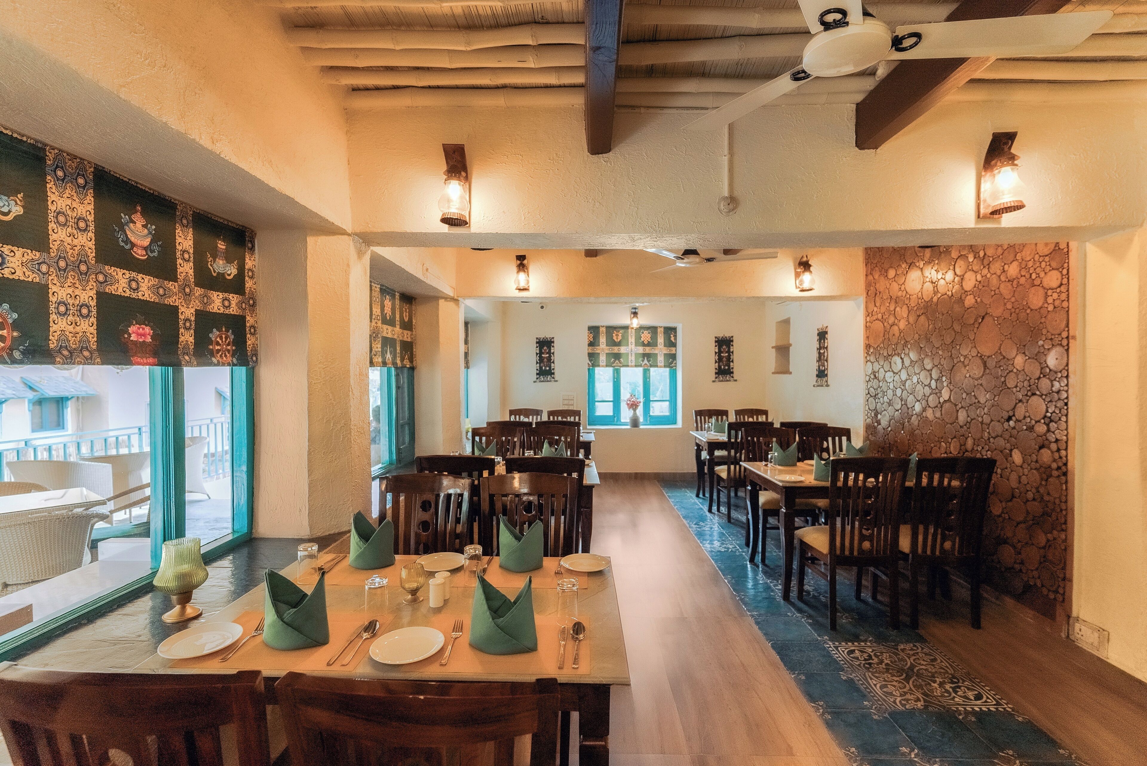 Un comedor con mesas y sillas de madera, un muro con diseño y vistas amplias a través de grandes ventanales.
