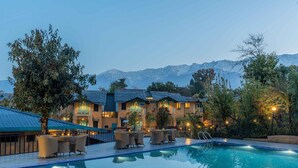 A hotel with a swimming pool, outdoor seating, and mountain views. - Tree of Life Birdsong Chalets (Dharamshala)