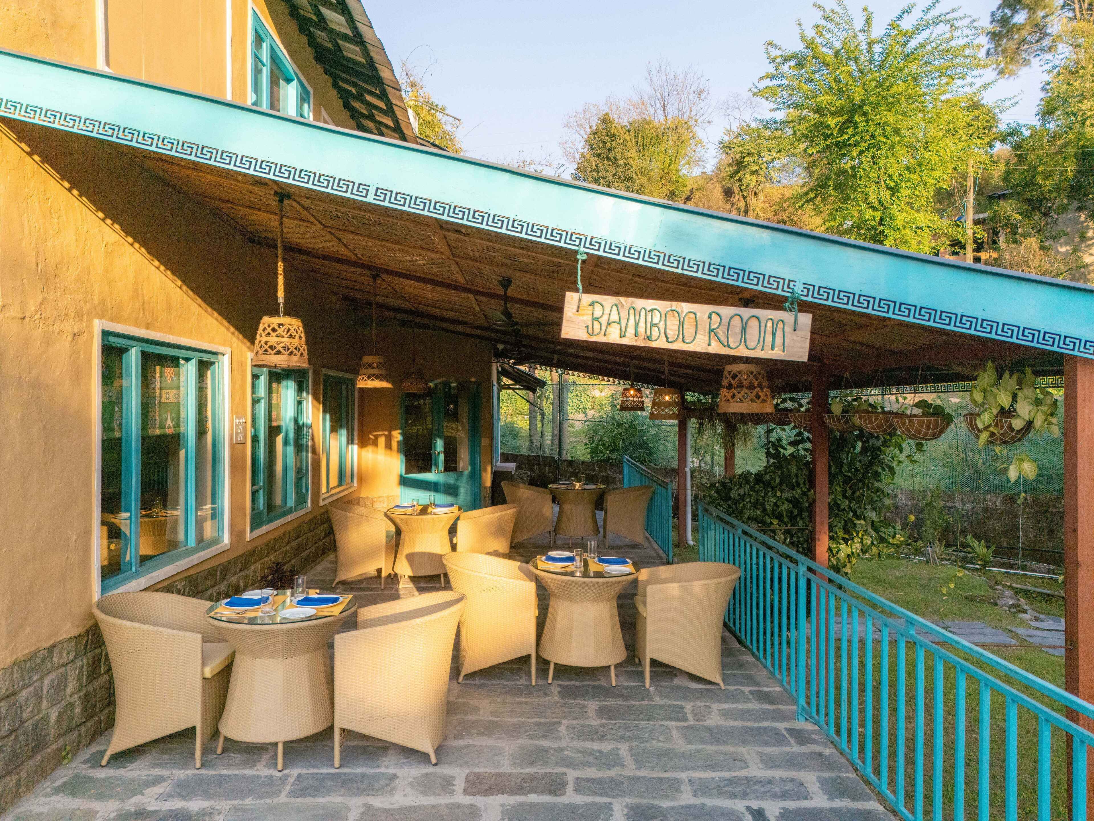 A covered outdoor seating area with wicker furniture and a sign reading "Bamboo Room".