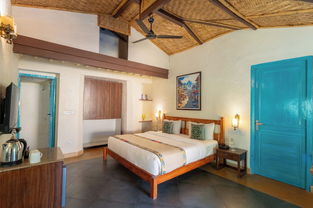 A bedroom with a wooden bed, a blue door, a ceiling fan, and a painting on the wall.
