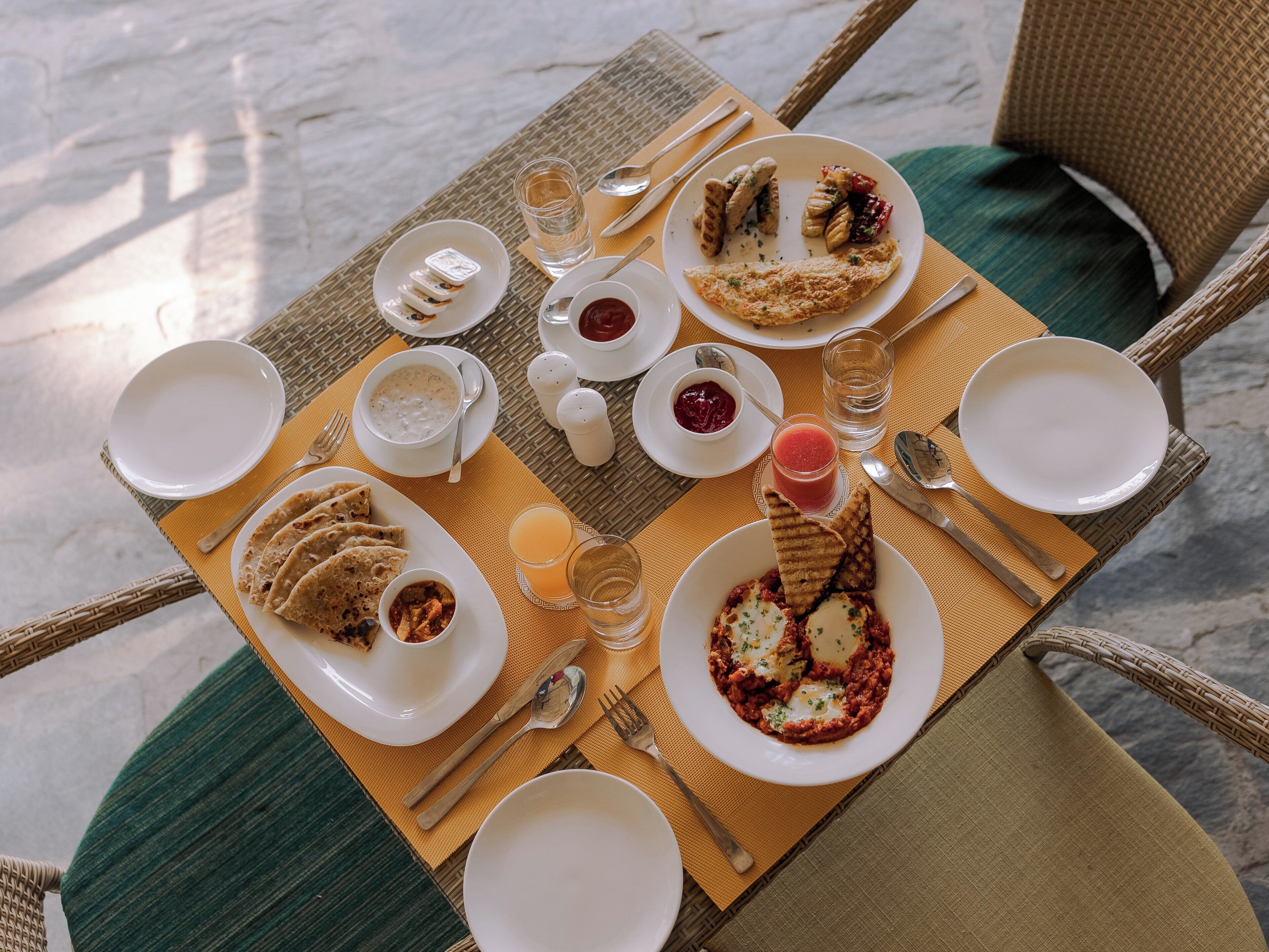 A table set with various dishes, including a plate of flatbreads, a bowl of soup, and a glass of juice.