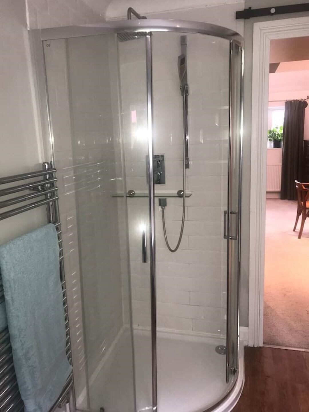 Une douche fermée par des parois en verre, dotée d’un pommeau de douche à main et d  ’un panneau de commande.