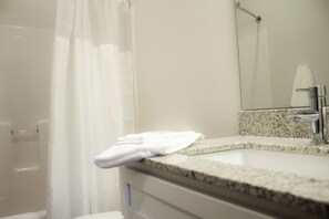 A bathroom with a shower curtain, a sink with a towel, and a mirror. - Stunning 4-BR Houses with On-Site Pool (Bloomington)