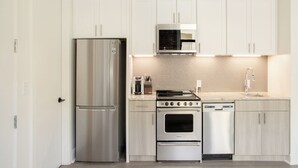 Uma cozinha moderna com eletrodomésticos de aço inoxidável, incluindo geladeira, micro-ondas, fogão e lava-louças.