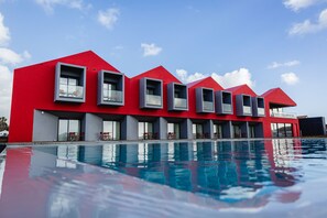 A modern hotel with a red facade, multiple balconies, and a swimming pool. - Pico TERRAMAR & SPA (Madalena)
