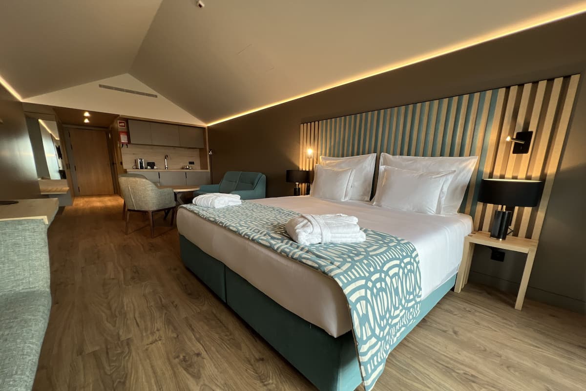 Une chambre d’hôtel moderne dotée d’un grand lit, d’un coin salon et d’une kitchenette.