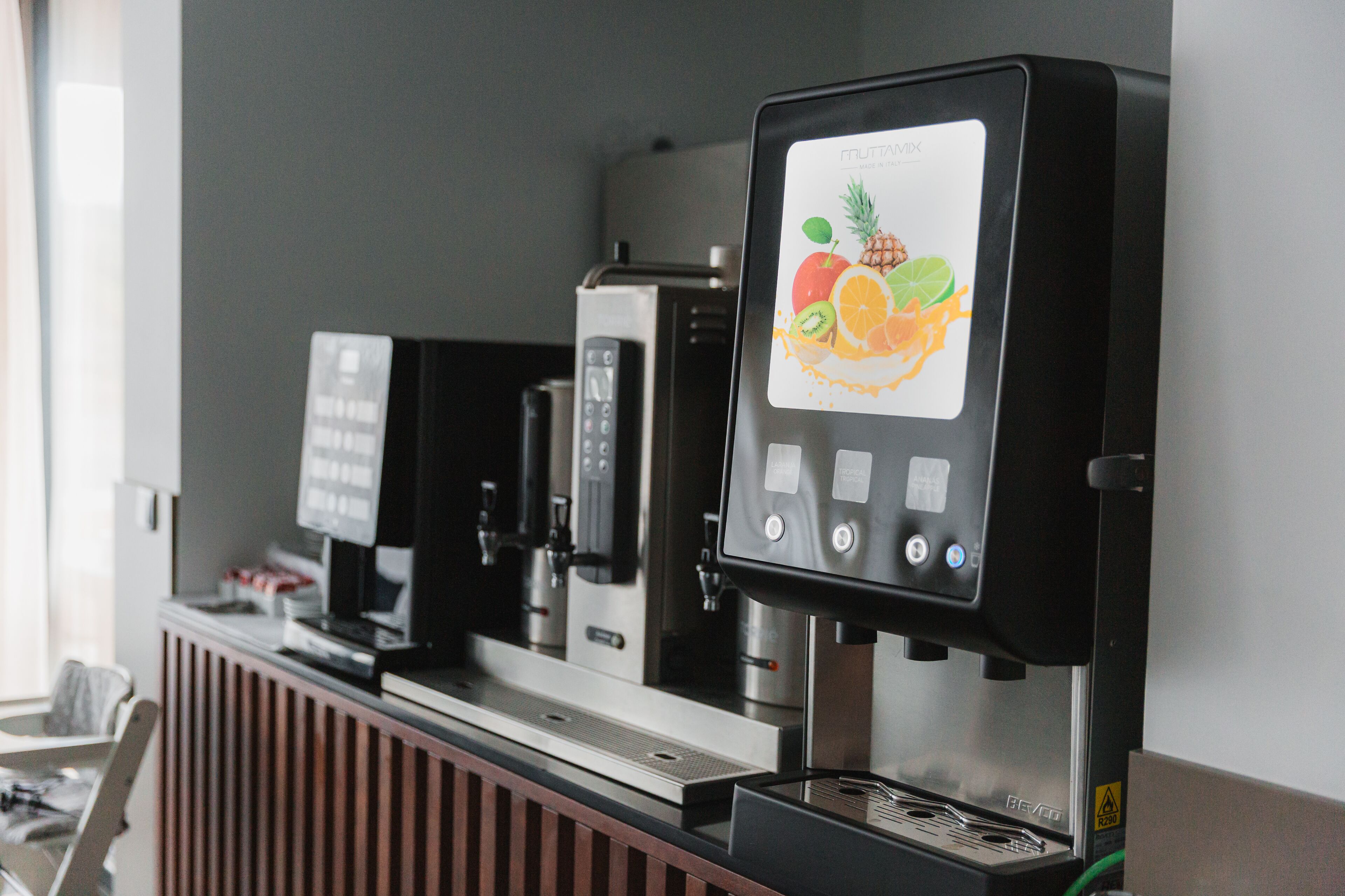 Une machine à café dotée d’un écran affichant des motifs de fruits et d’un panneau de commande.