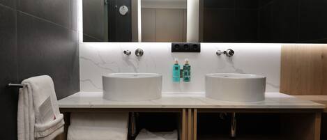 Une salle de bain moderne avec deux lavabos, un grand miroir et un porte-serviettes.