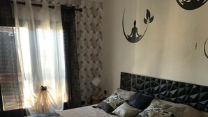 A bedroom with a large bed, a headboard with a geometric pattern, and a wall with a silhouette of a meditating figure. - Villa Nyvioni, Proche de la mer Avec Piscine et SPA (Agde)