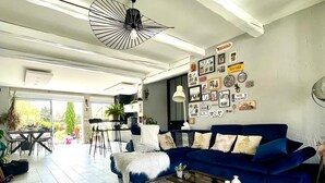 A modern living room with a blue sofa, a white rug, and a ceiling fan. - Villa Nyvioni, Proche de la mer Avec Piscine et SPA (Agde)