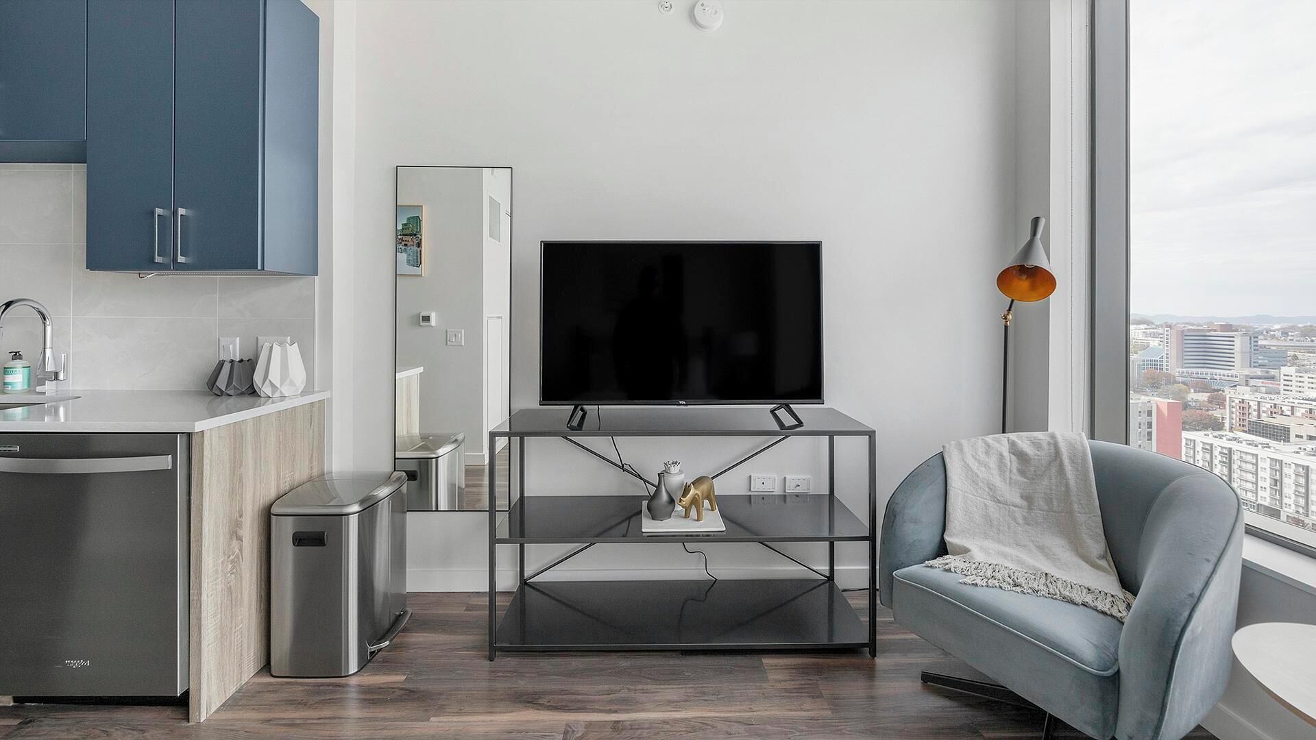 Un salon moderne avec un téléviseur, un canapé, une table basse et une vue sur la ville.
