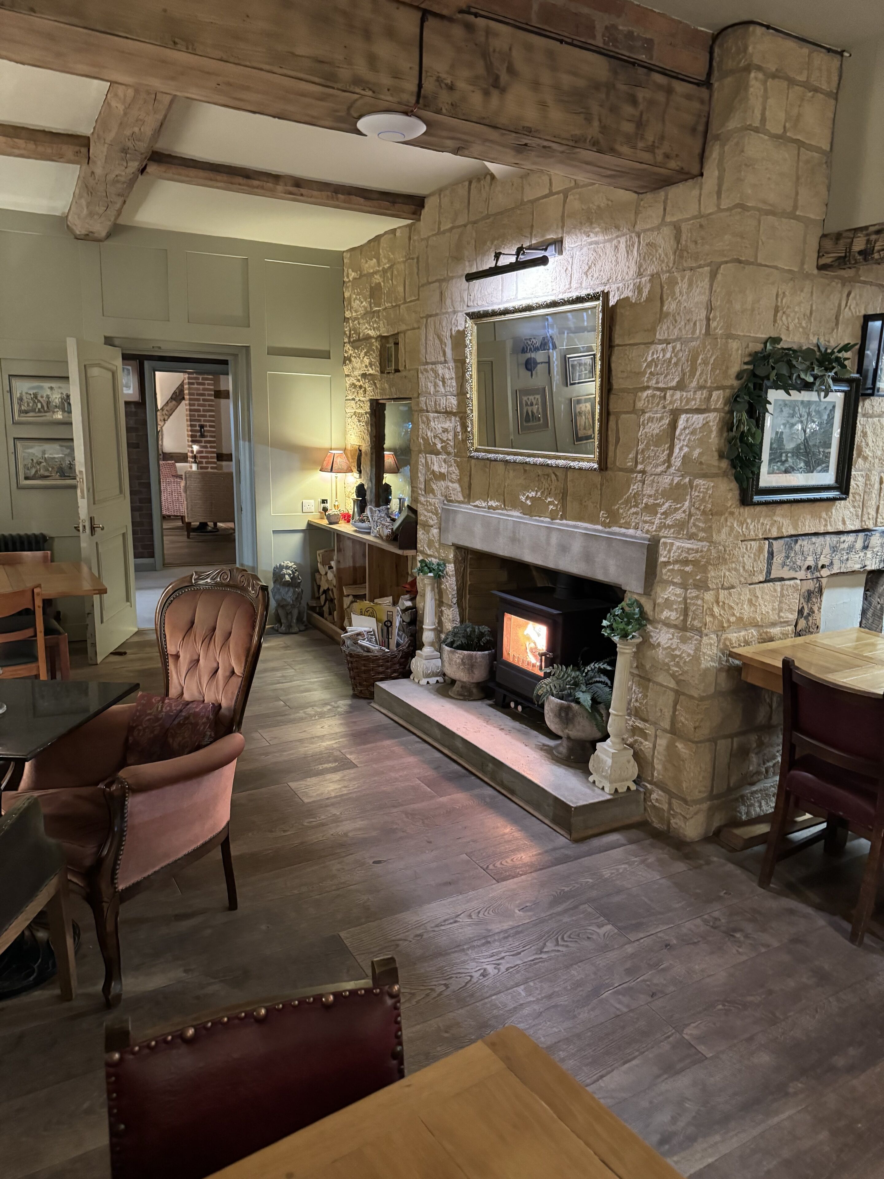 A cozy living room with a stone fireplace, wooden furniture, and a view into another room.