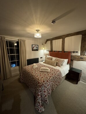 A bedroom with a large bed, a window with curtains, a radiator, a wall-mounted light, and a ceiling fan. - White Lion Hotel (Worcester)