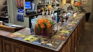 Zona de bar con una barra larga, estanterías con botellas y un monitor de ordenador.