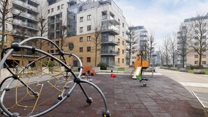 Una bicicleta estacionada sobre pavimento mojado, con edificios de apartamentos al fondo.