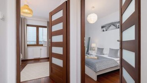 Un dormitorio moderno con cama, mesita de noche y vistas a la ciudad a través de una ventana.