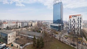 Un área urbana moderna con un rascacielos de vidrio imponente, un edificio de diseño único y varias construcciones más pequeñas.