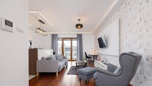 Una sala moderna con un sofá gris, un sillón gris y piso de madera.