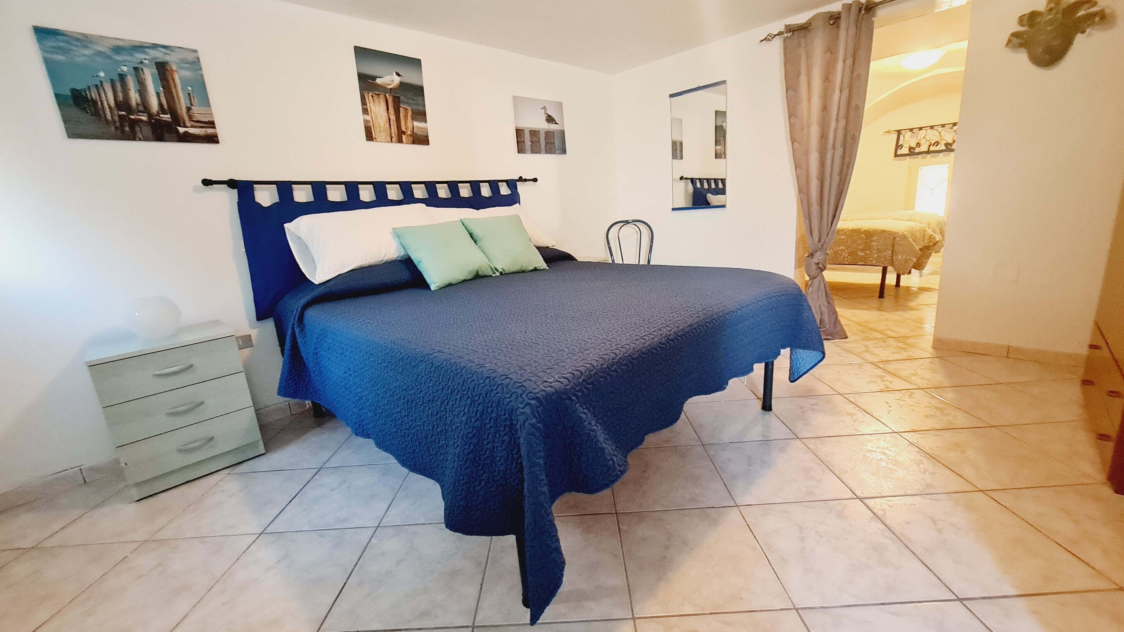 A bedroom with a bed, a nightstand, a dresser, and a mirror.