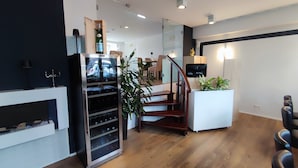 Een moderne keuken met een wijnkoeler, een houten trap en een wit kookeiland.