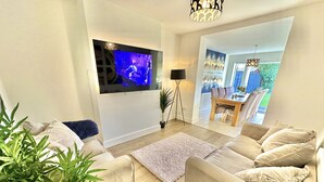 Una sala de estar moderna con un televisor de pantalla plana montado en la pared, un sofá, una mesa de centro y una planta en maceta.