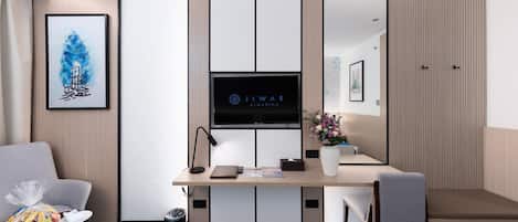 Una habitación de hotel con escritorio, silla, televisor y un espejo grande.