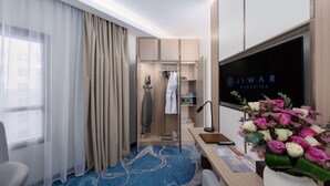 Ein Hotelzimmer mit Bett, Schreibtisch mit Computer, Fernseher, Kleiderschrank und Bad.
