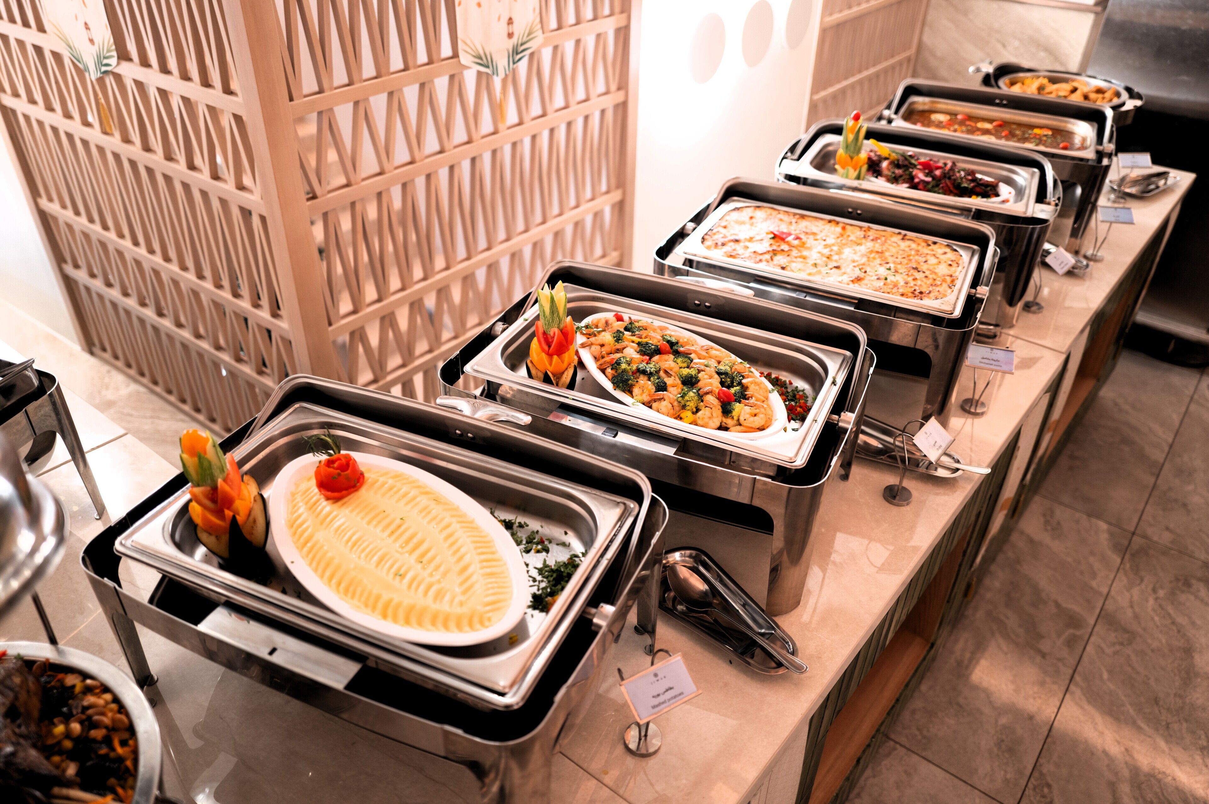 Una mesa de buffet con diversas opciones de comida y una pared decorativa al fondo.