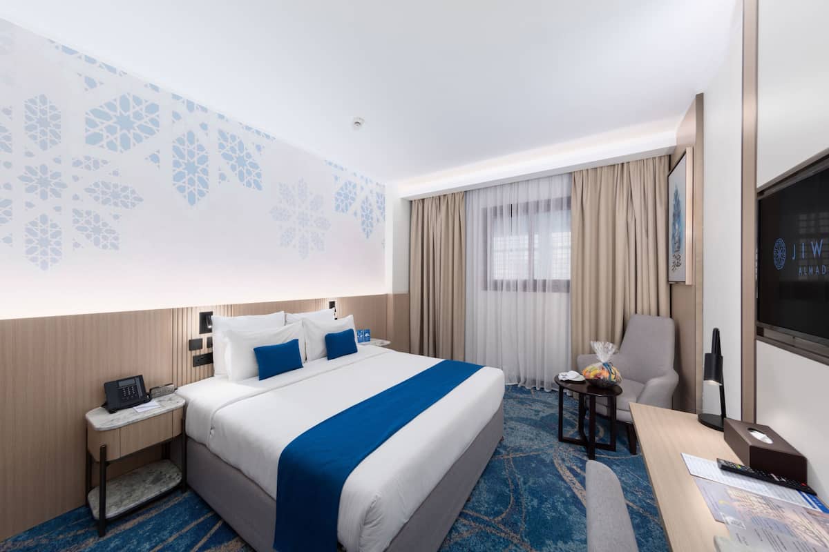 Een hotelkamer met een groot bed, een bureau, een stoel, een televisie en een telefoon op het nachtkastje.